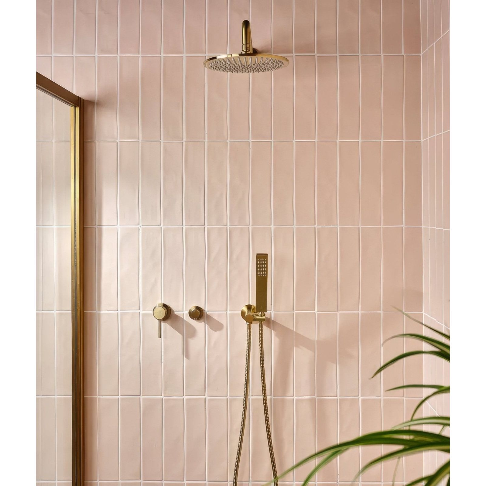 Gold-toned rain showerhead with sleek modern design mounted on pink tiled wall in fondant ceramic rose finish