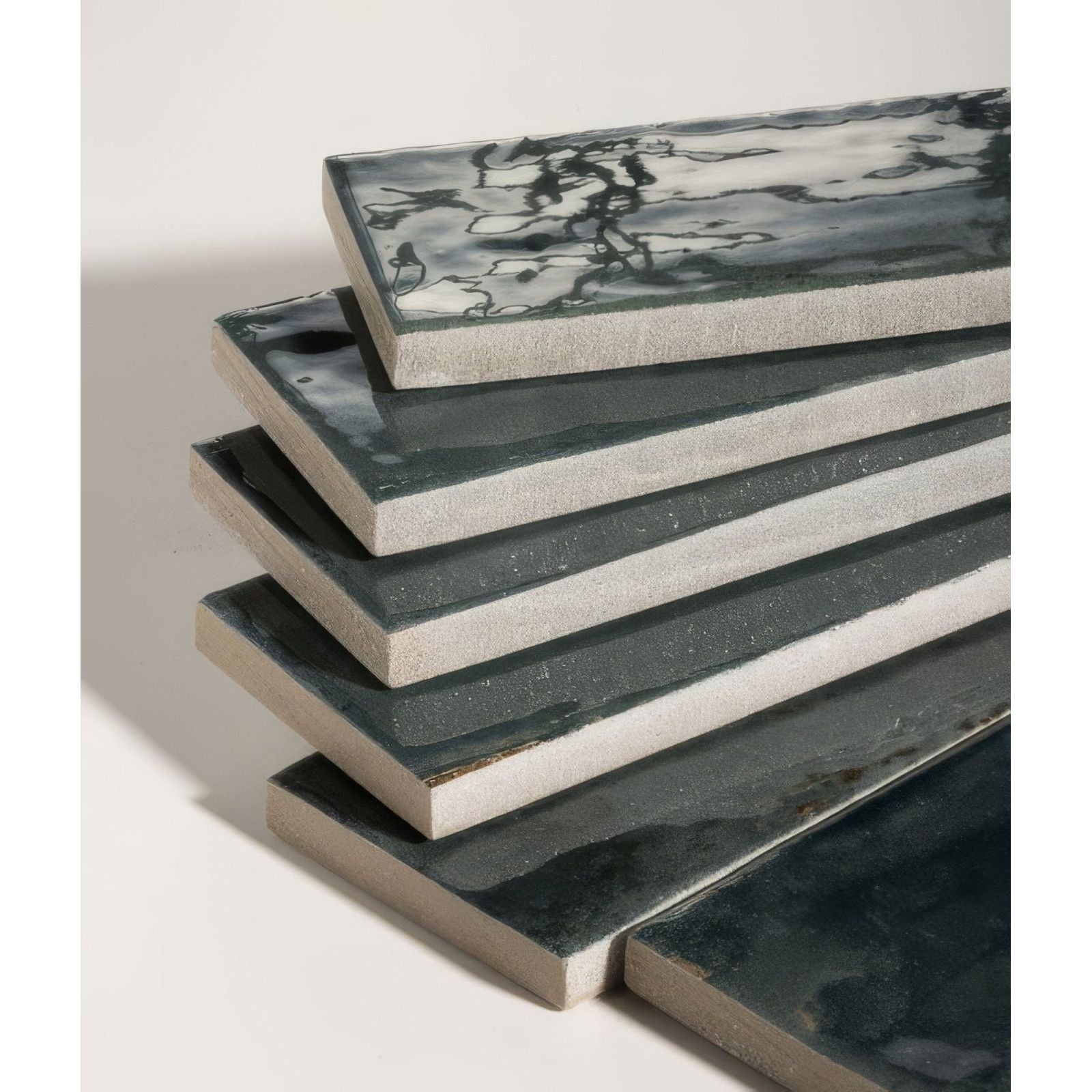 Stacked rectangular ceramic tiles with a matte gray and black marbled glaze finish.