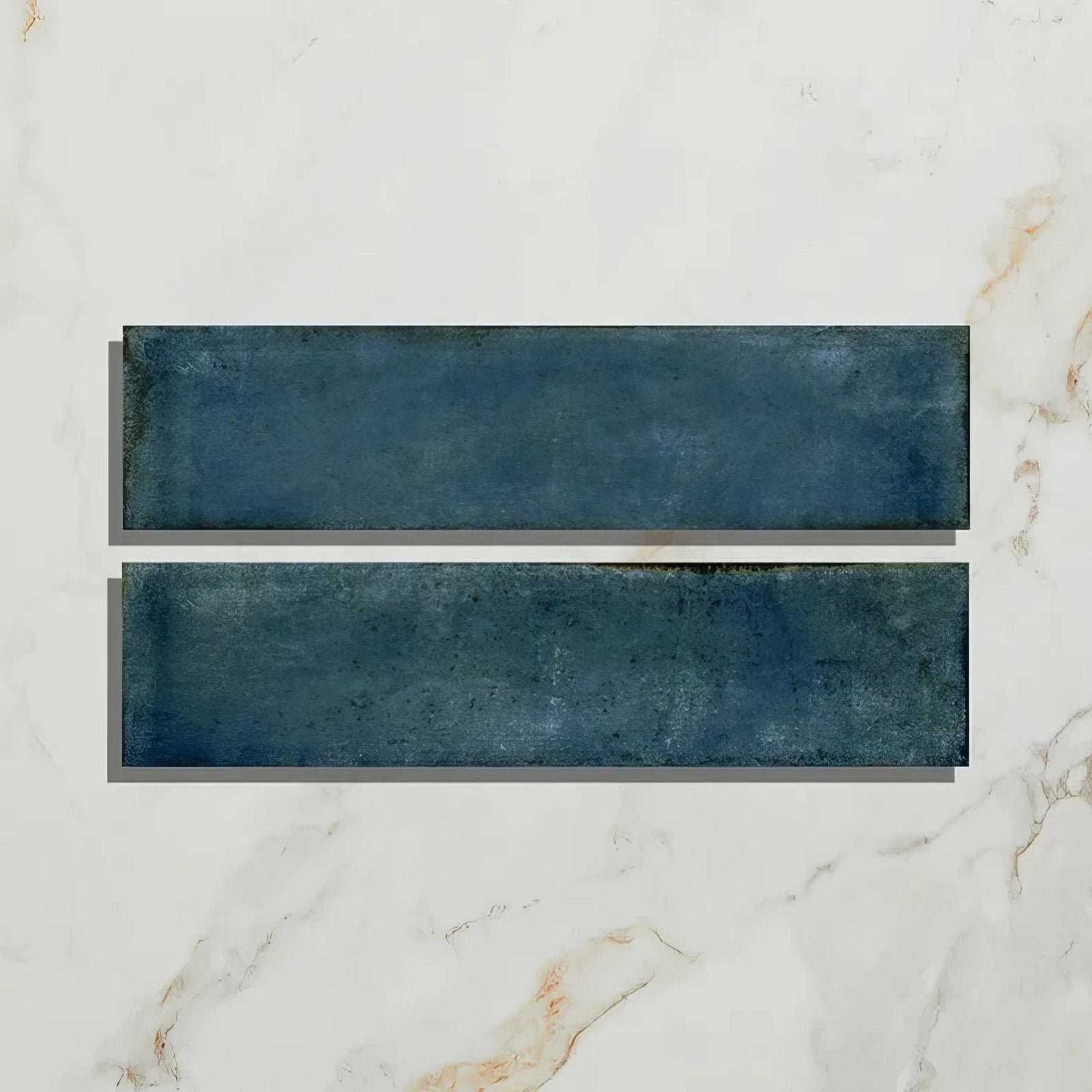 Two rectangular navy blue foundry porcelain blue ceramic tiles with textured matte finish on white marble surface