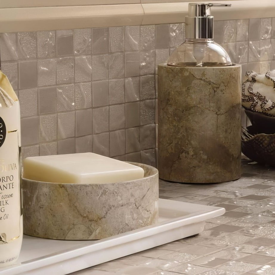 A beige marble soap dish holding a rectangular pale yellow soap bar from four seasons spring mosaic collection