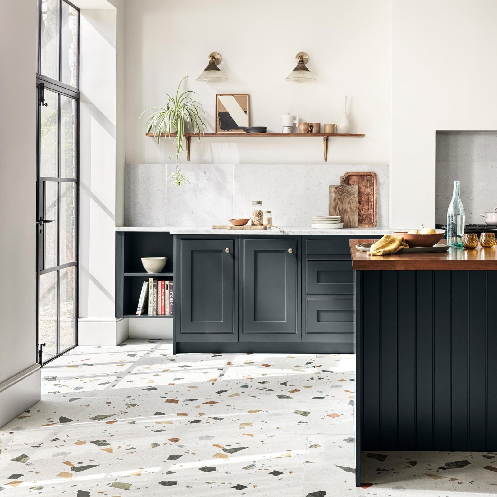 Dark gray shaker-style kitchen cabinets with recessed panel doors and round brass knobs paired with frammento multi terrazzo effect porcelain tile