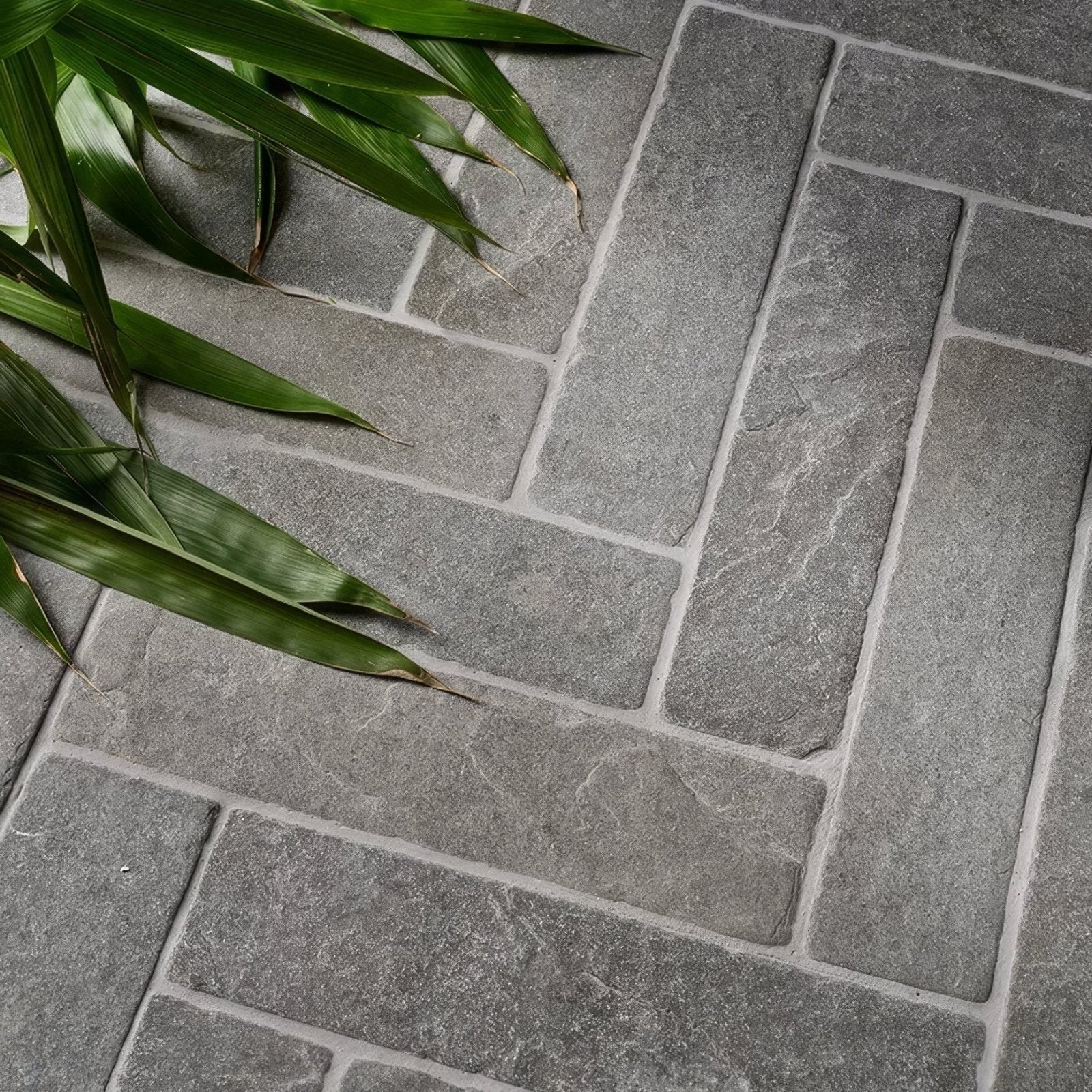 Gray stone tiles in a herringbone pattern with natural texture and subtle veining galway limestone seasoned parquet