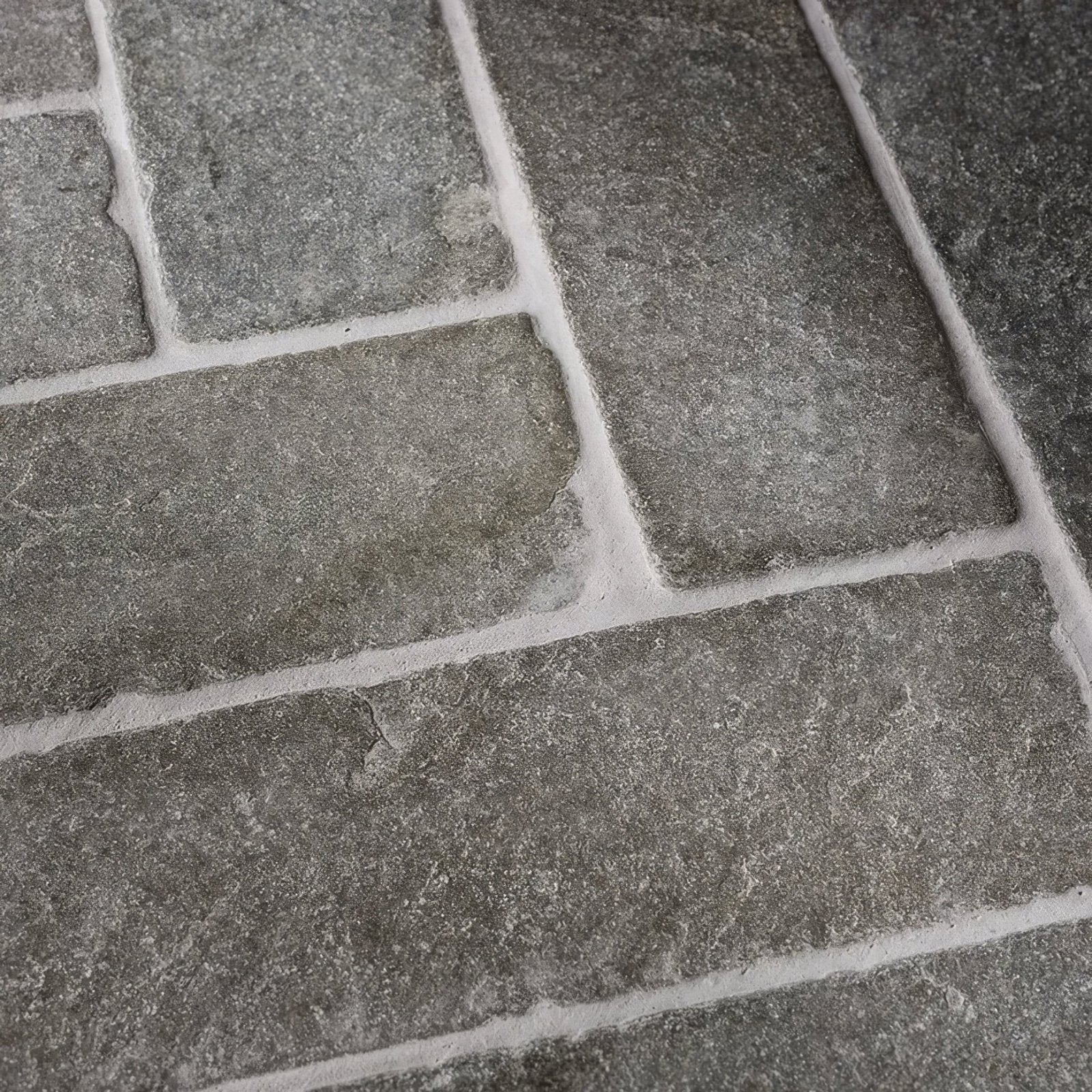 Dark gray rectangular seasoned parquet stone tiles with rough textured surface and white grout lines made of galway limestone