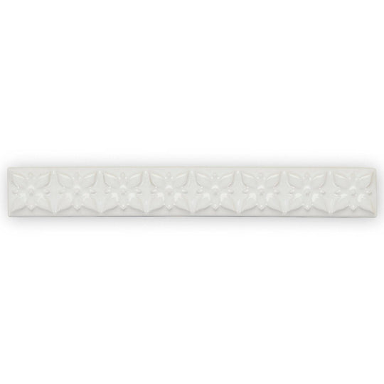 White ceramic tile giralda cascara cream trim with a repeating embossed floral pattern for wall decoration