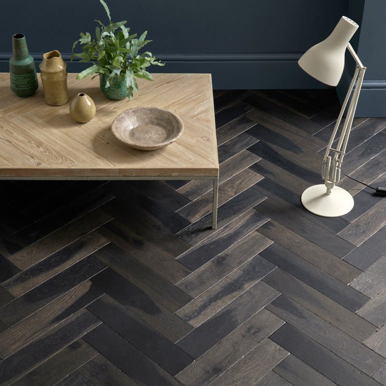 Dark gray herringbone patterned hardwood floor planks in goodrich charred oak finish