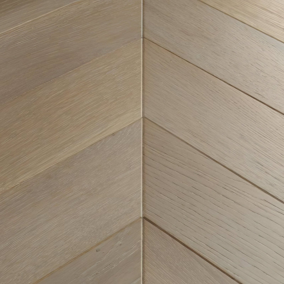Light beige hardwood flooring with subtle wood grain in a herringbone layout goodrich feather oak chevron