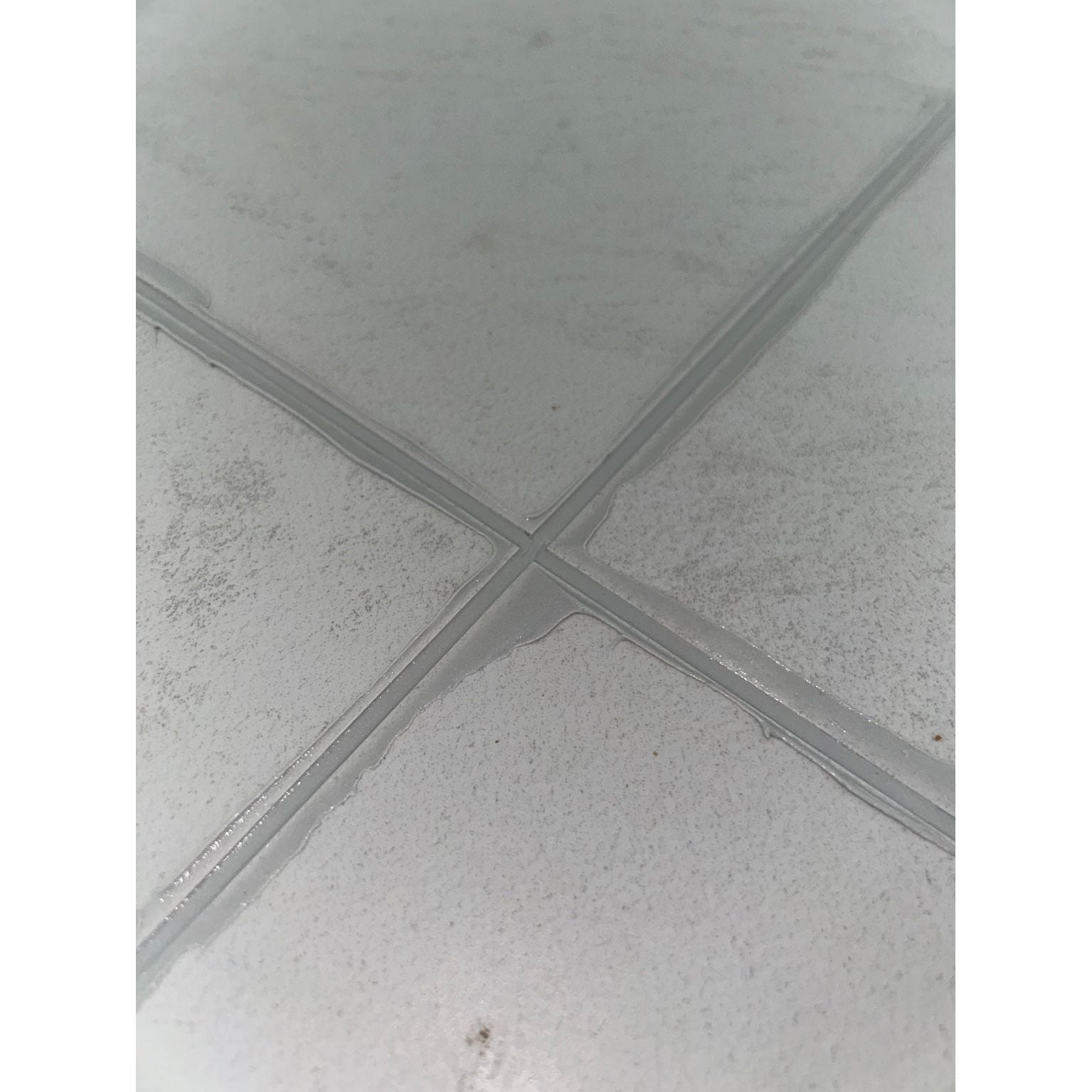 Gray tiled floor with goPoxy epoxy grout forming intersecting grout lines in an x-shape for durable flooring