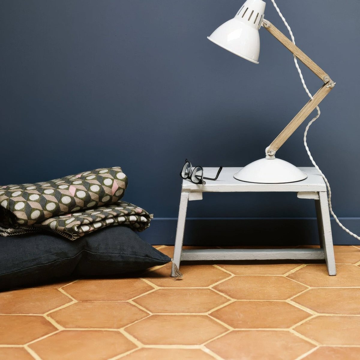 White metal desk lamp with wooden articulated arm featured alongside handmade classic terracotta hexagonal tile