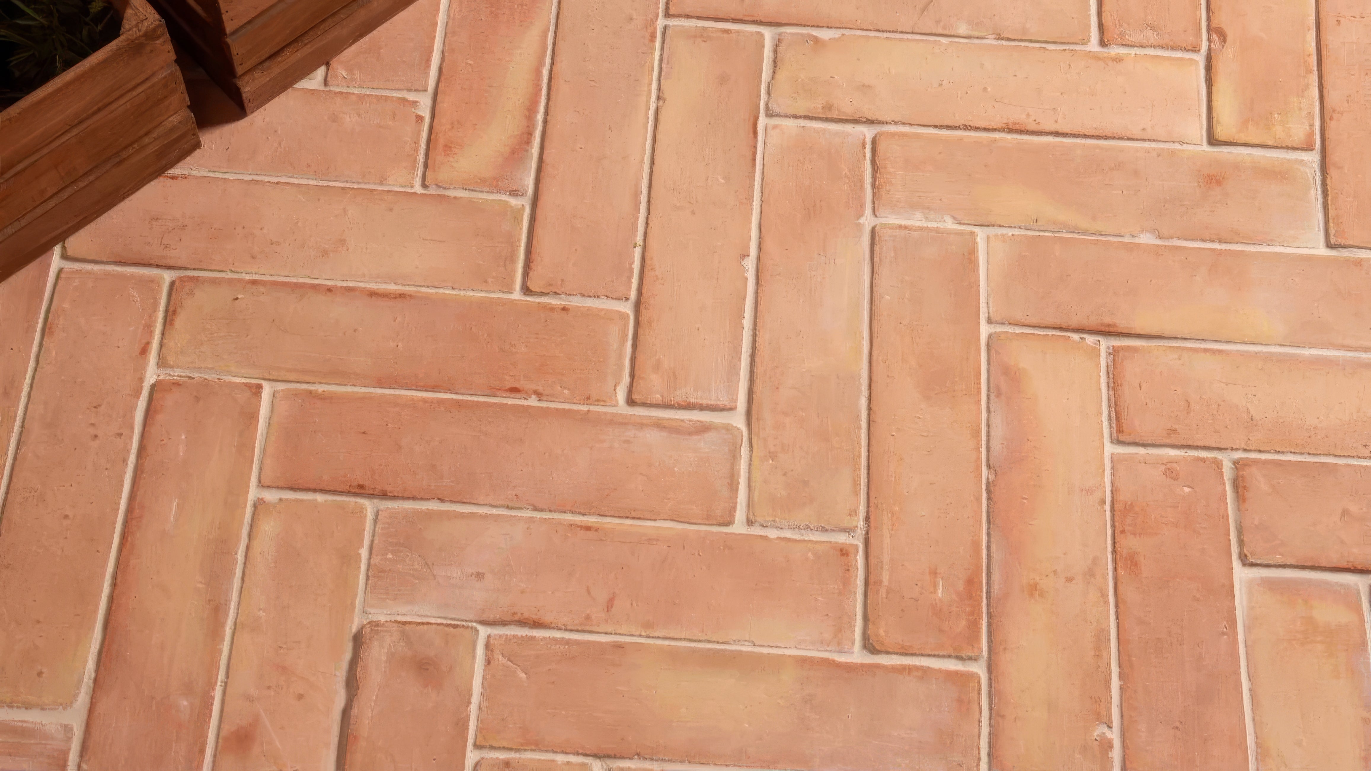 Terracotta tiles arranged in a herringbone pattern on a floor.
