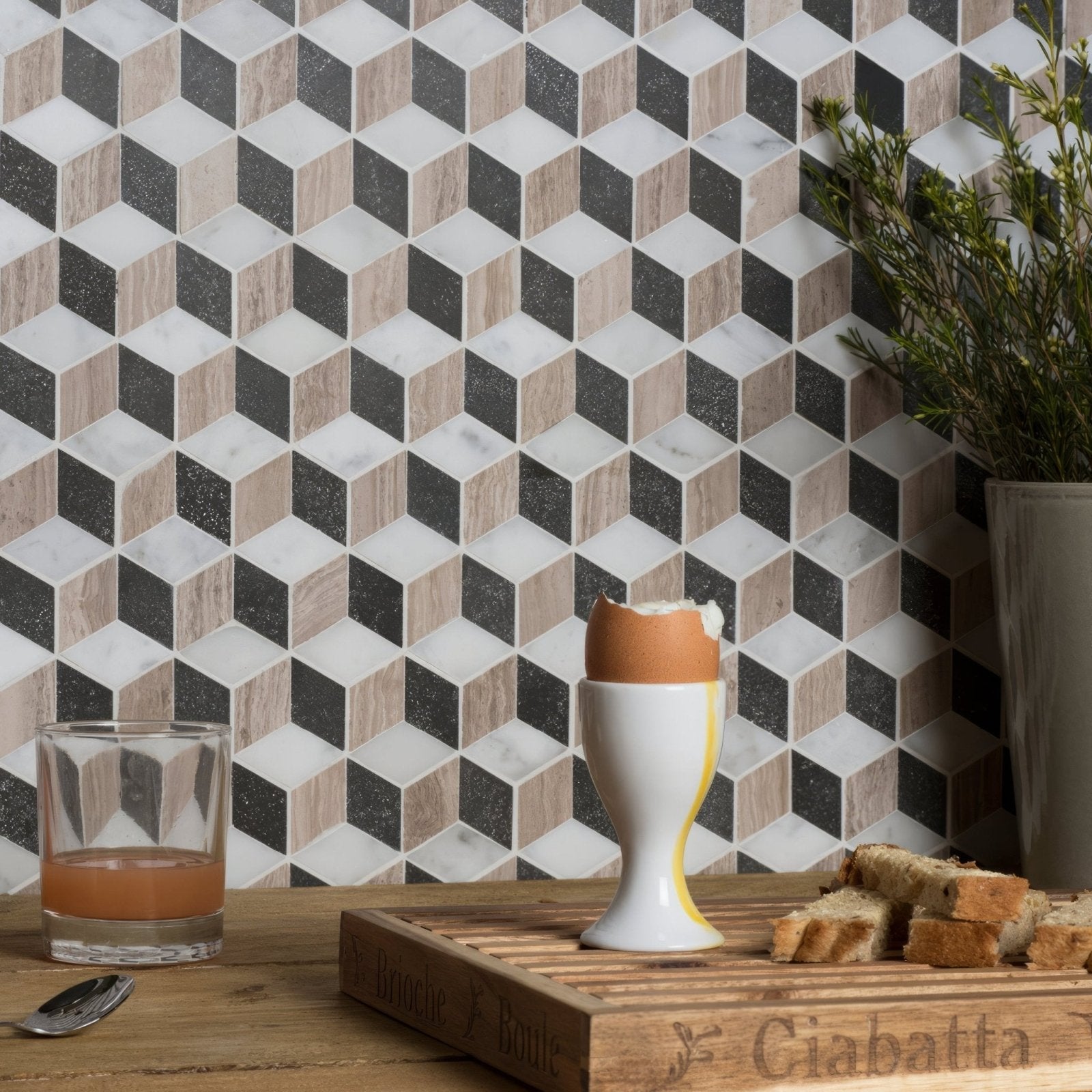 White ceramic egg cup with yellow accent holding cracked hard-boiled egg in herald marble mosaic design