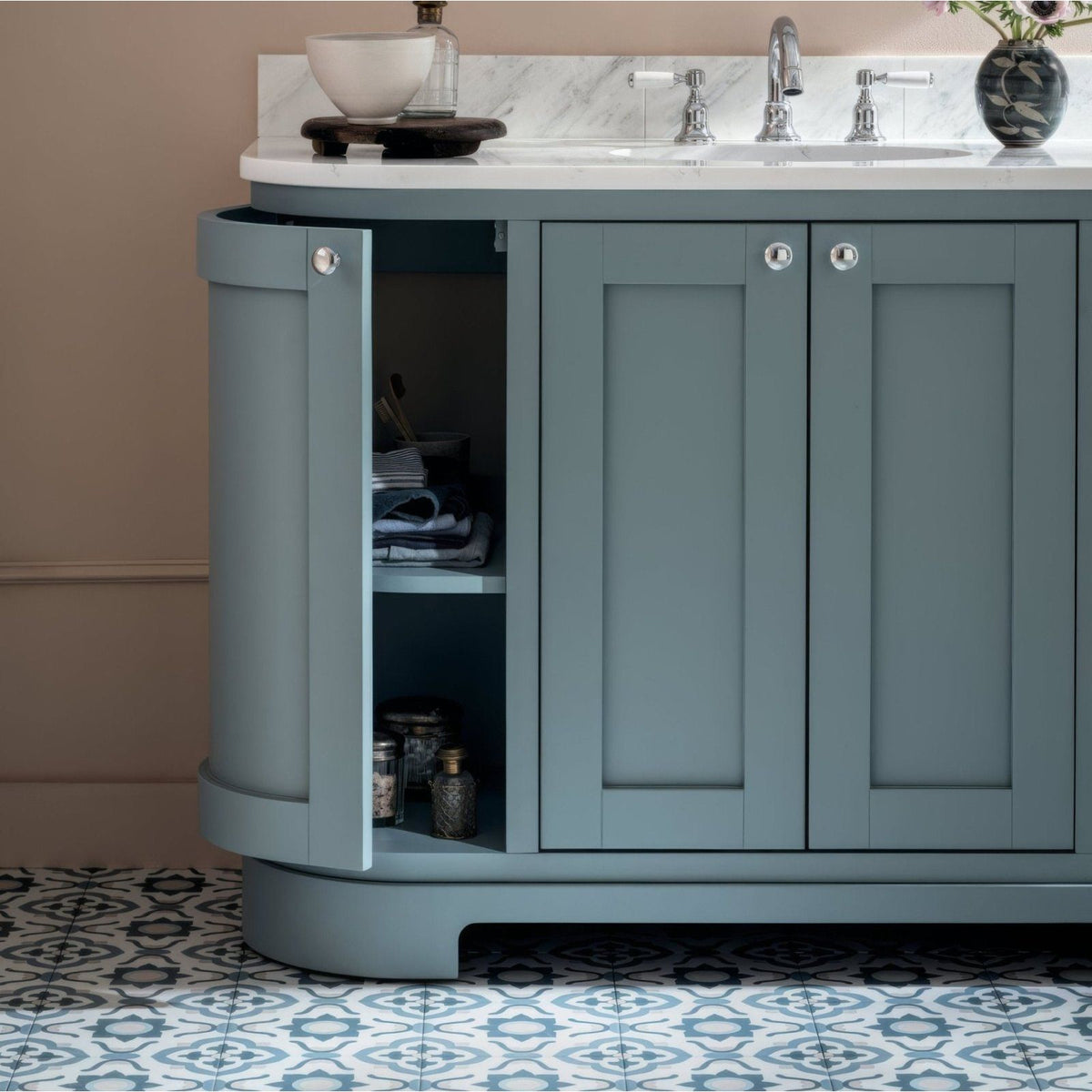 A sleek sage green bathroom vanity with curved side panel and silver hardware featuring infusion nazare patterned tile