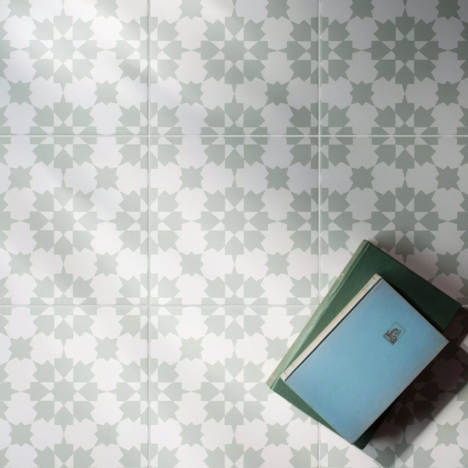 Stack of books with light blue and dark green covers featuring simple rectangular labels for infusion ornelas patterned tile design
