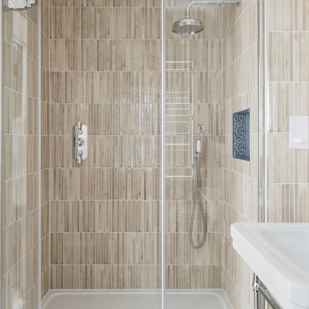 Modern shower enclosure featuring ixworth ivory bar tile with sleek vertically striped beige ceramic tiles and chrome rainhead