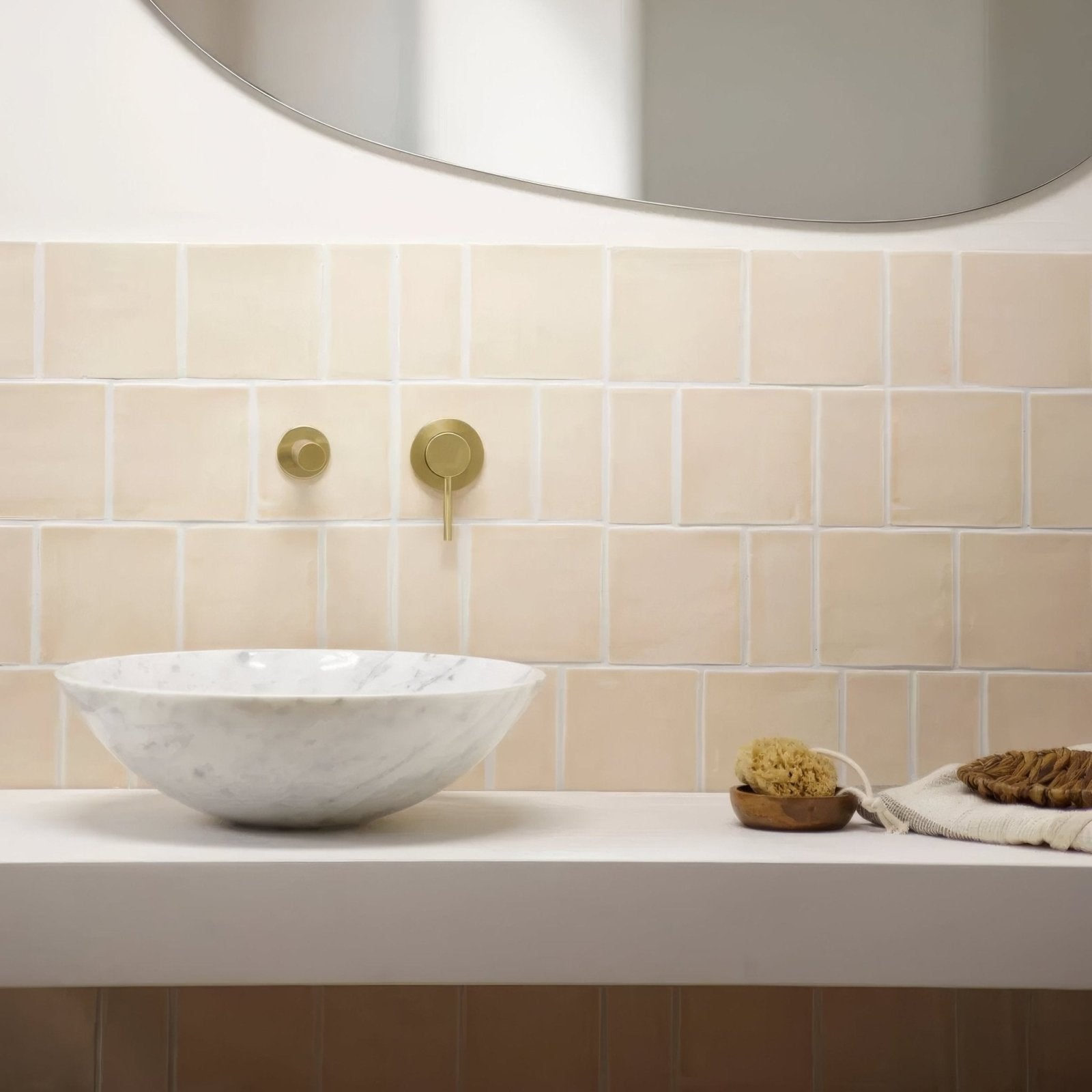 A white marble bowl sink with subtle gray veining mounted on a sleek countertop featuring jaipur old ochre square glazed tile
