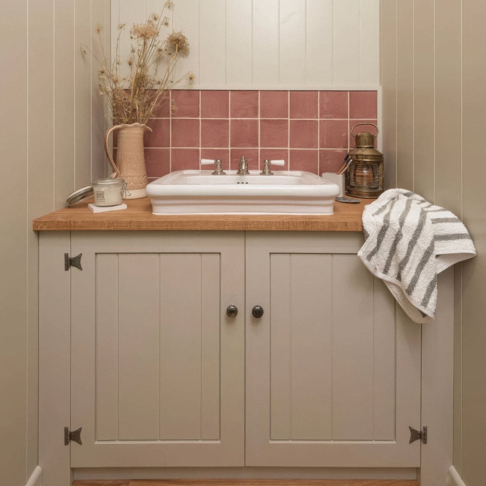 White rectangular ceramic sink with silver faucet set into wooden countertop above light gray cabinets with jaipur pompeiian red tile