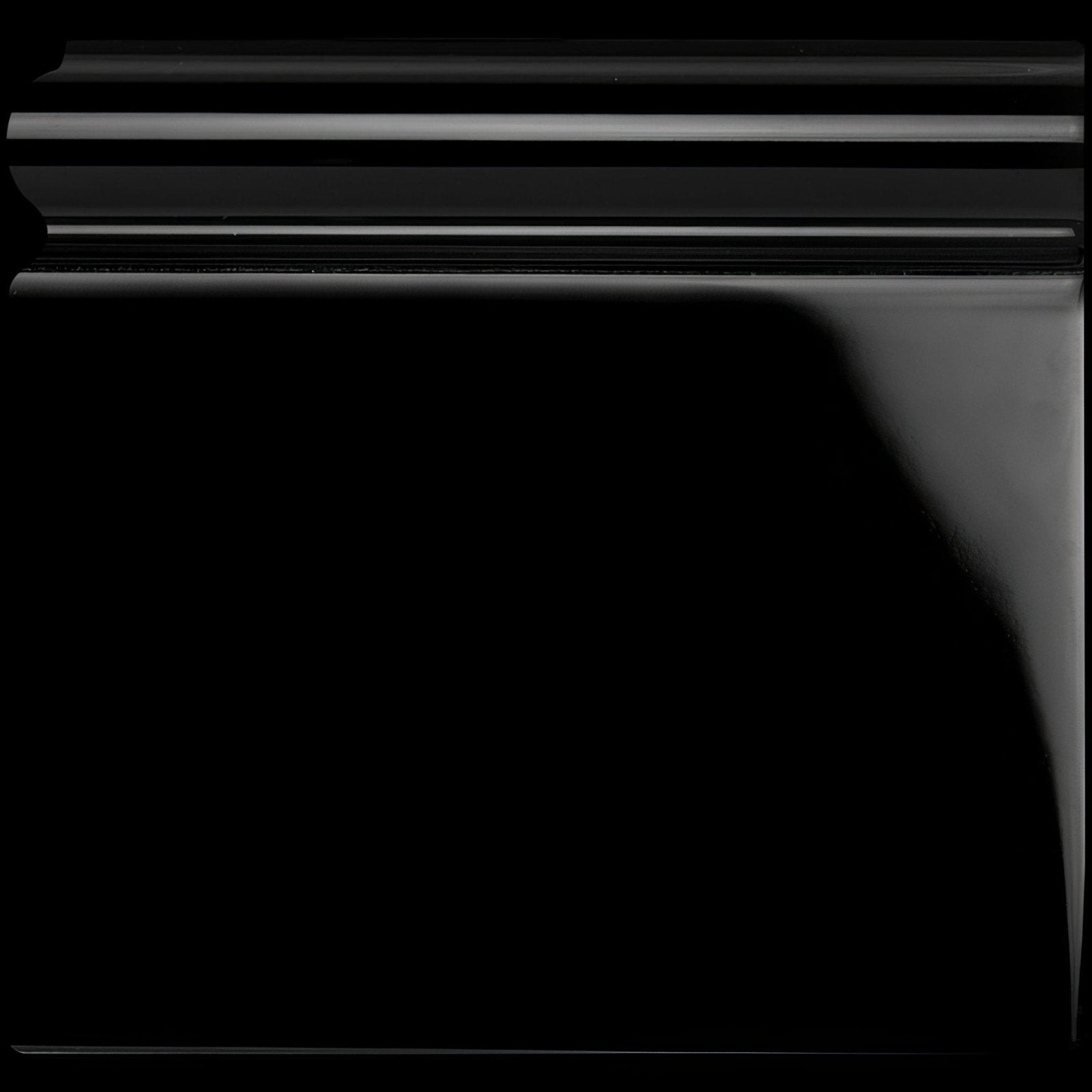 Jet black skirting left corner with black glossy crown molding featuring smooth reflective surface and horizontal grooves
