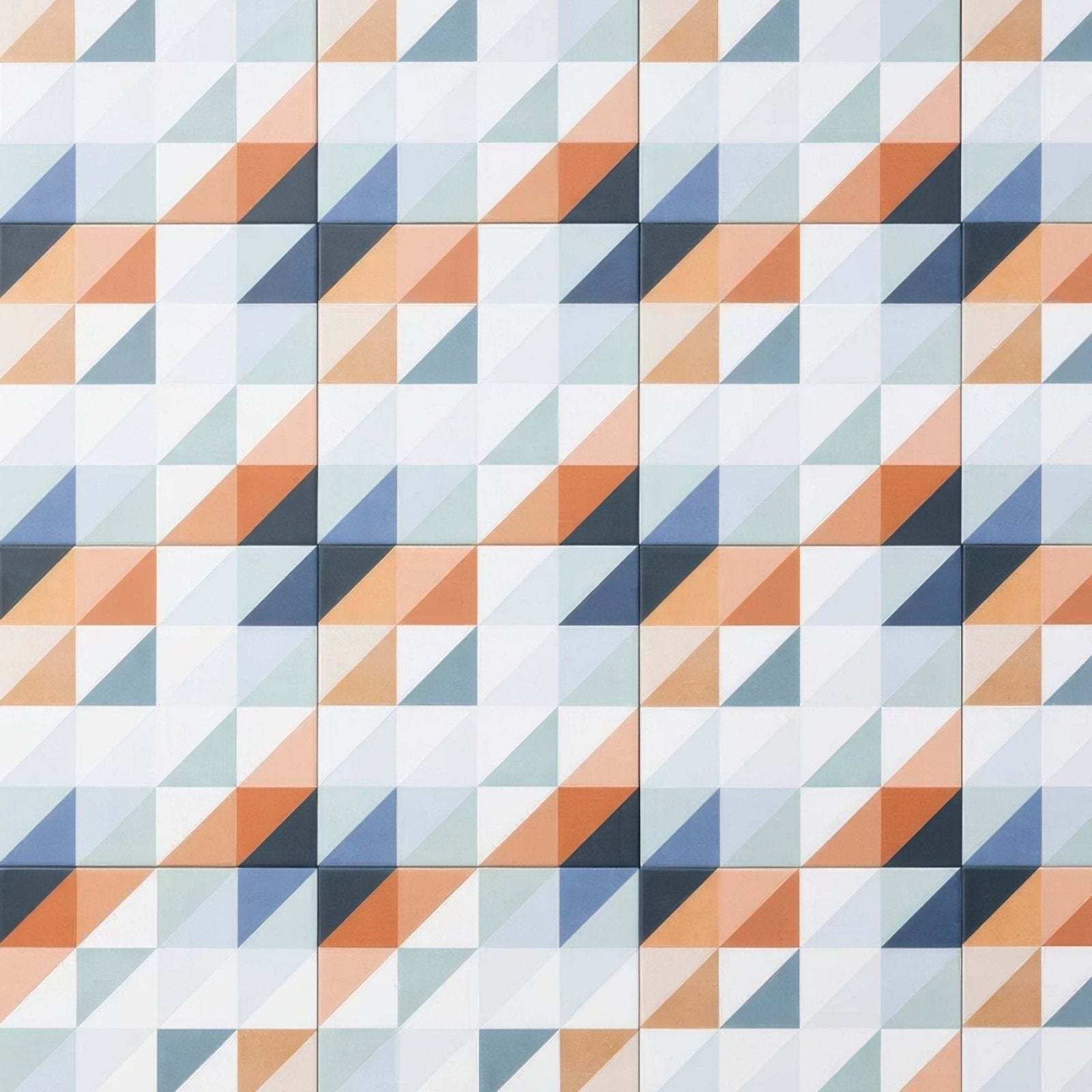 Geometric tile wall with interlocking triangles in muted orange blue-gray and white from kaleidoscope porcelain peacock collection