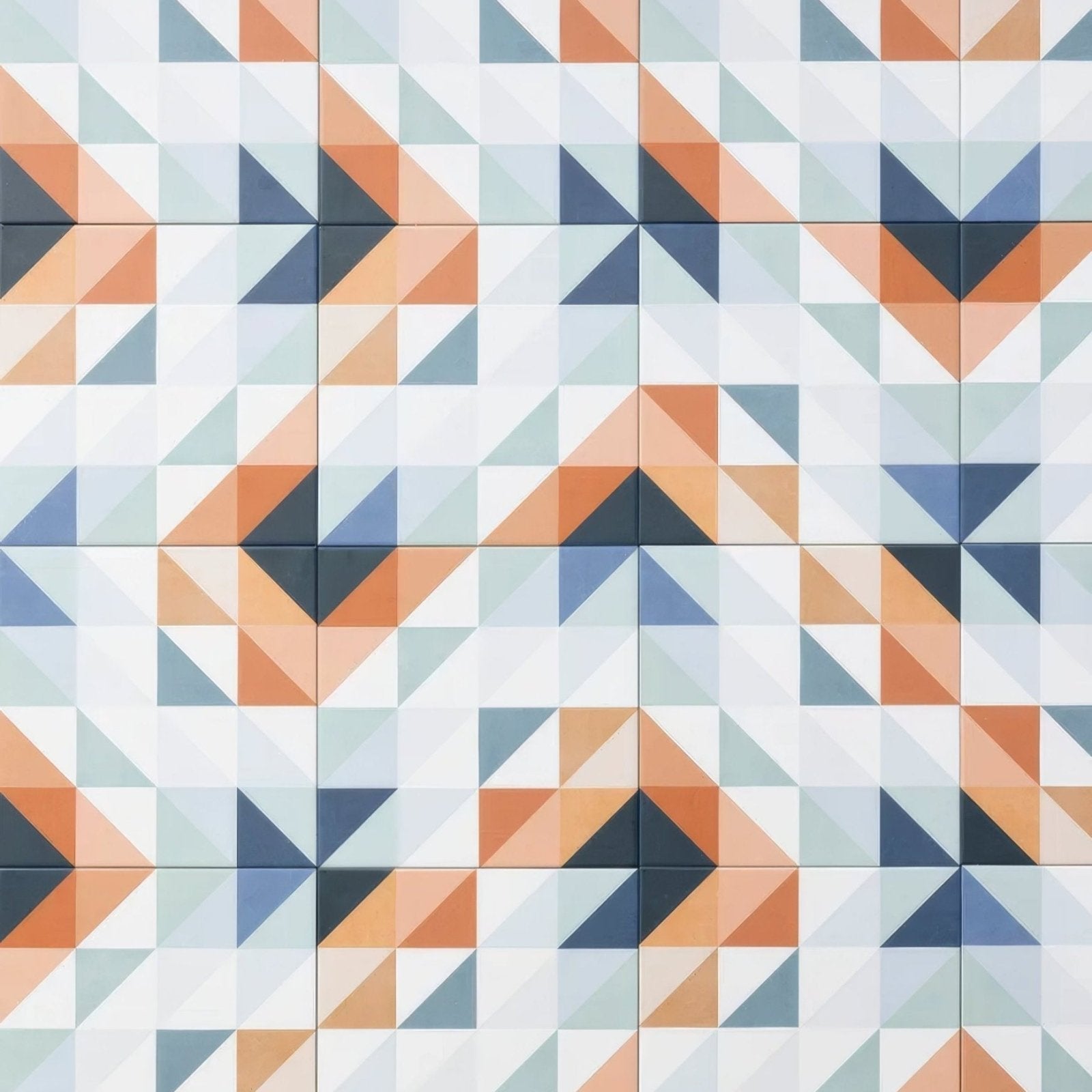 Geometric patterned kaleidoscope porcelain peacock ceramic tiles featuring orange navy blue and muted gray triangles on white