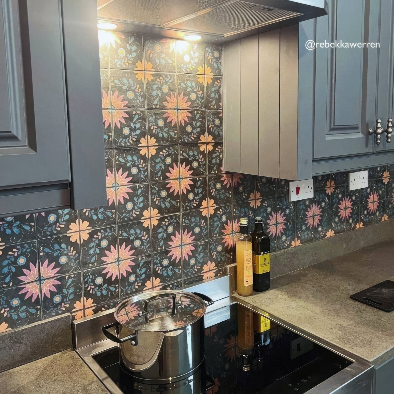 Stainless steel pot with lid on induction cooktop displayed on kelmscott blackwell patterned tile background