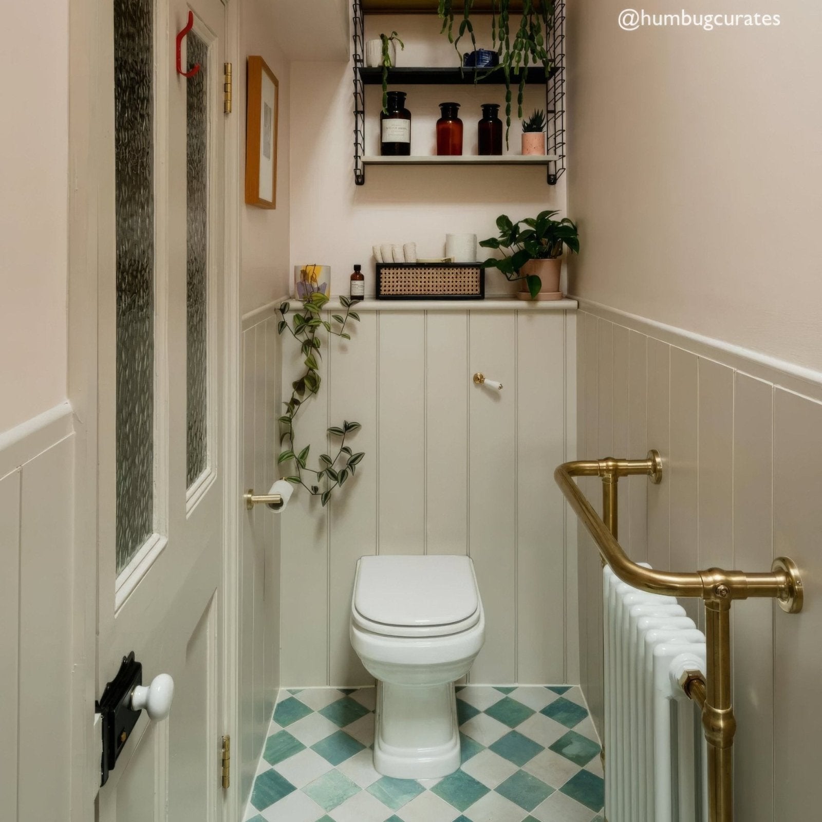 Bathroom with white toilet, gold radiator, and decorative elements.