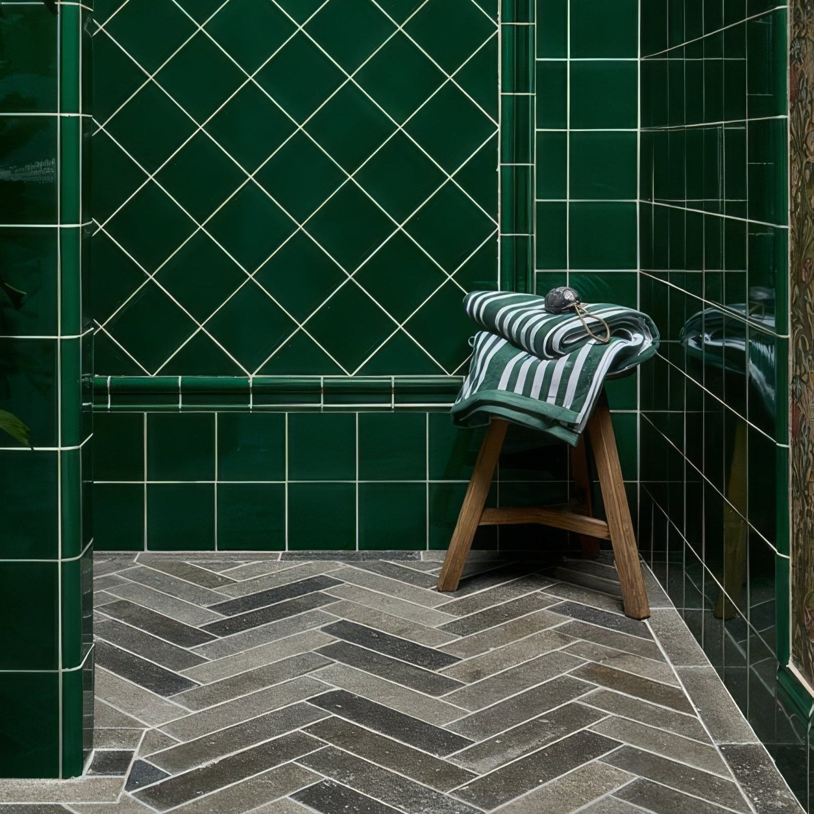 A rolled green and white striped towel resting on a wooden stool next to kimmeridge limestone tumbled and etched parquet
