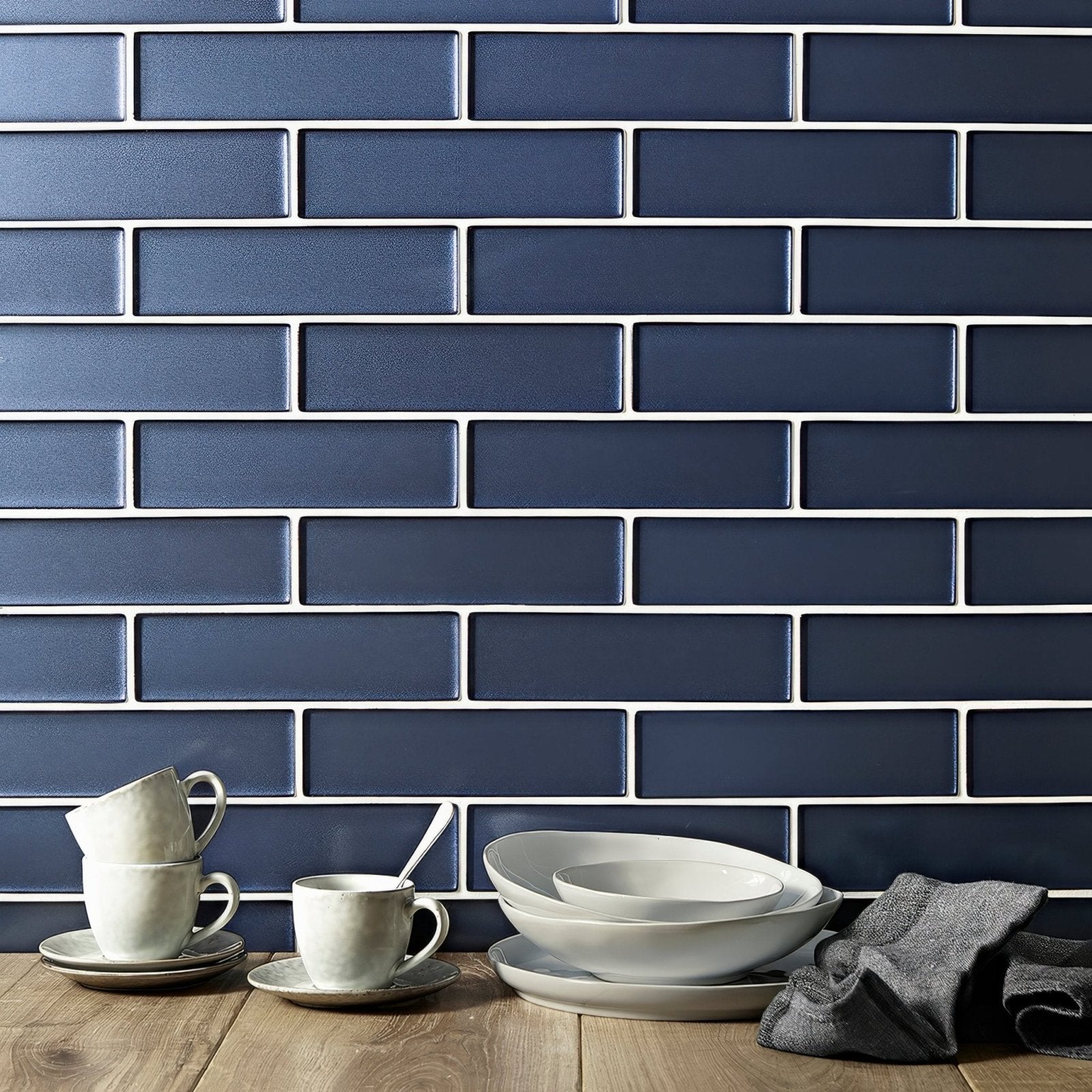Kingfisher blue glass wall tile features dark blue rectangular subway tiles with white grout for a sleek modern backsplash