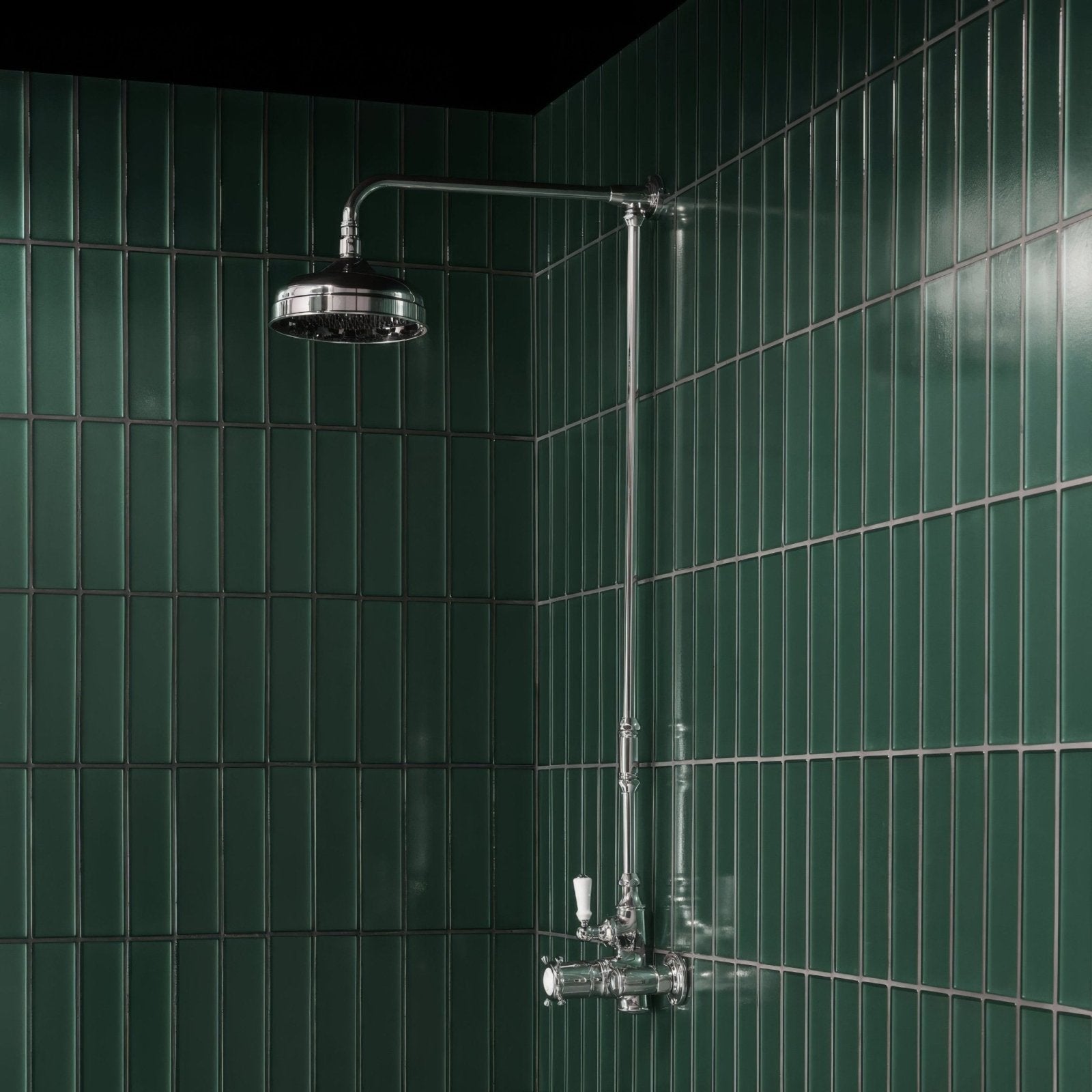 Chrome-finished classic style showerhead and faucet with curved arm mounted on kingfisher green glass wall tile