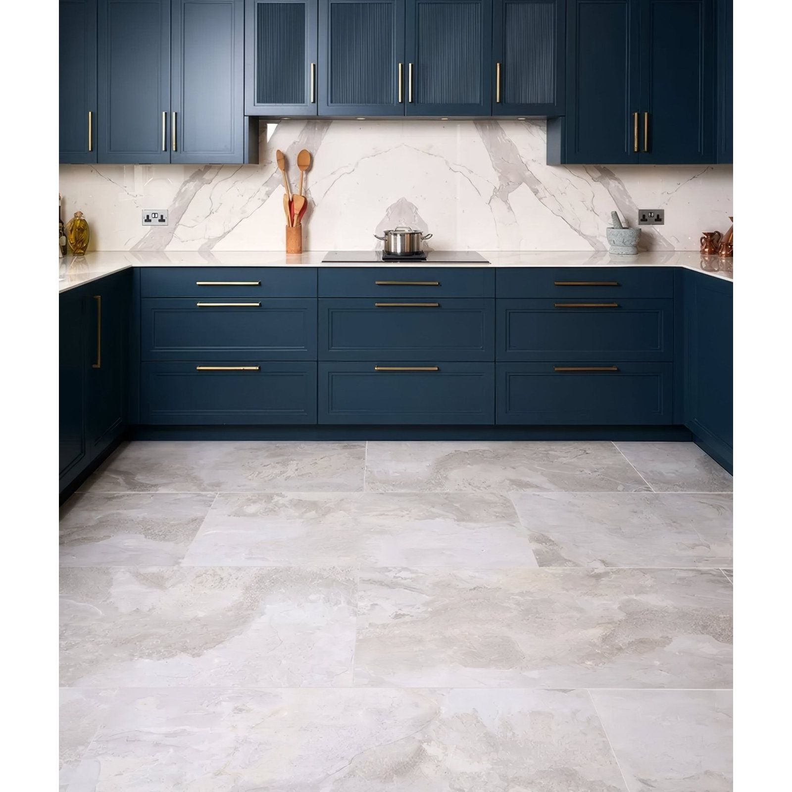 Komodo porcelain white countertop with deep blue cabinetry featuring sleek gold toned handles and marble pattern