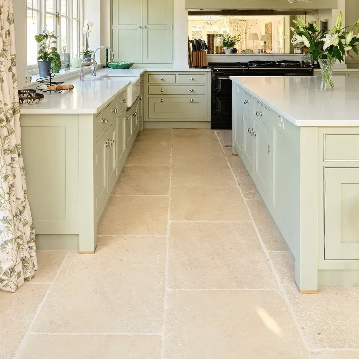Light green shaker-style kitchen cabinets with silver hardware and white countertops in lacock limestone heritage finish