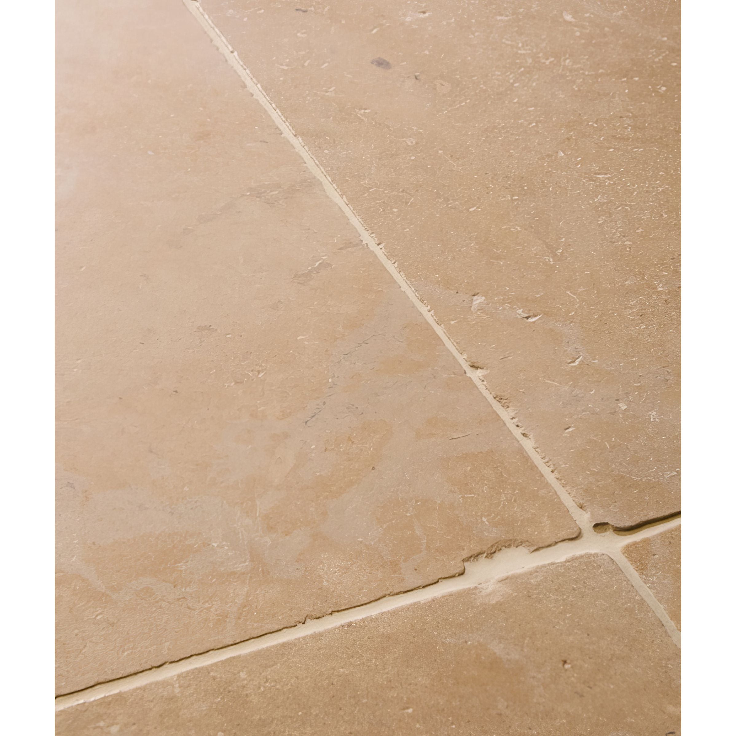 Close-up of beige tiles in Lacock Tumbled Limestone Flooring with a visible grout line