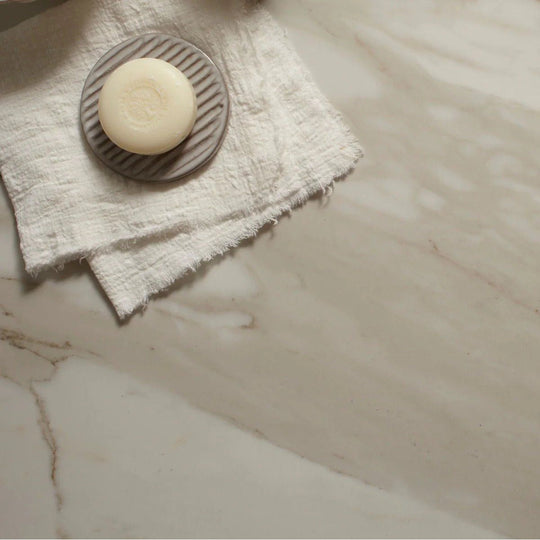 Lucca Calacatta Noble 60 x 120cm white marble-effect tiles with a round soap on a ridged dish