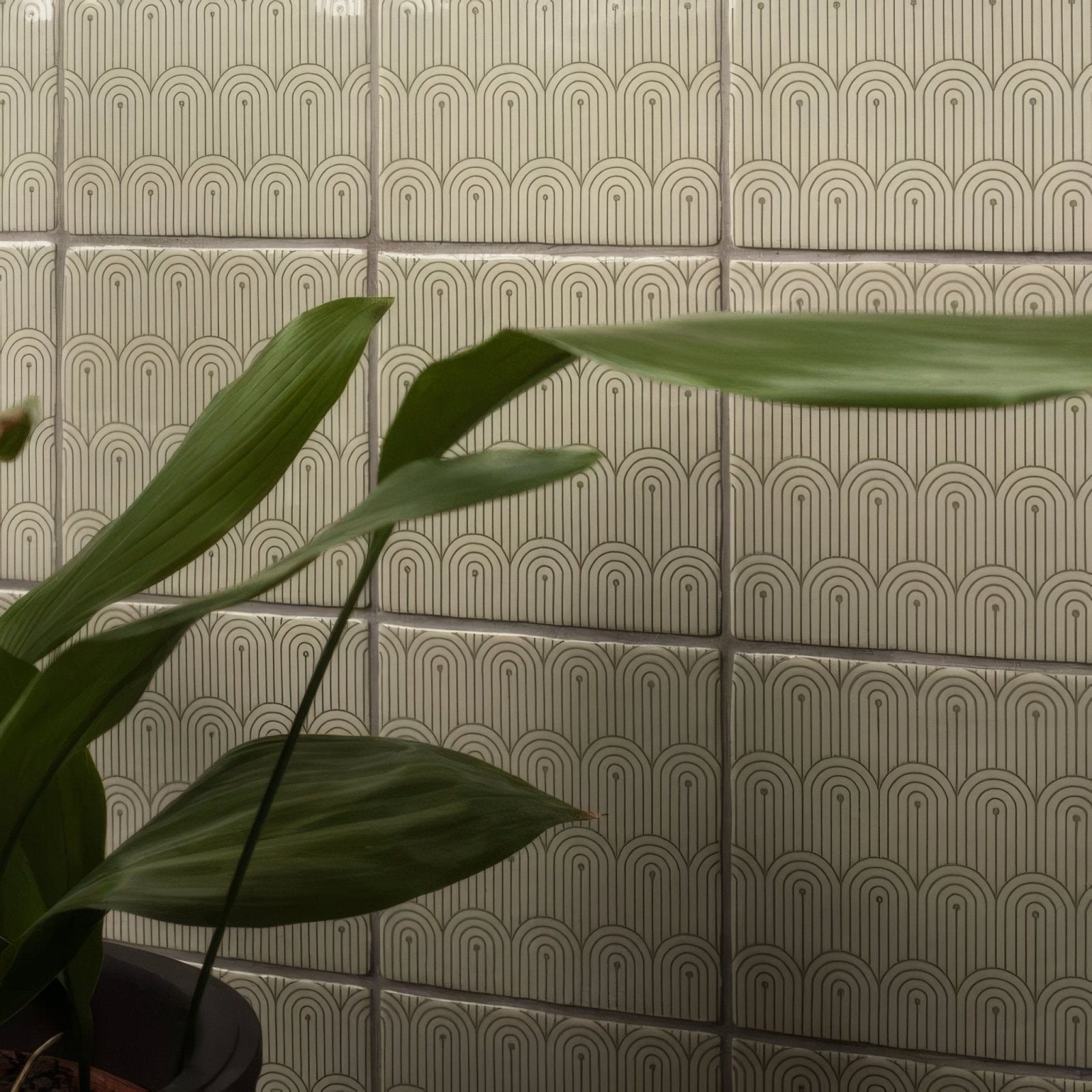 Beige ceramic Manoir Deco pumice tiles with a repeating geometric pattern of dark gray arches and lines