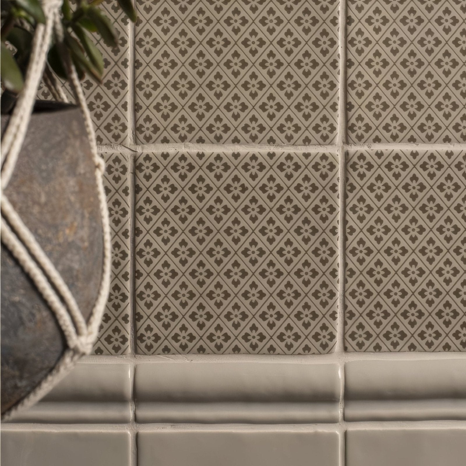 Beige ceramic tiles with a repeating dark brown geometric floral pattern from manoir provence pumice collection