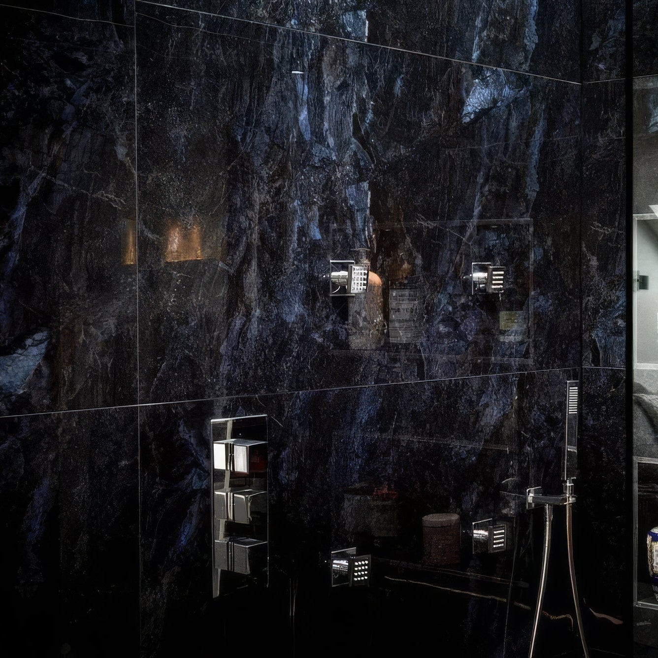 Bathroom with dark marble tiles in Marble Ocean Rock 60 x 120cm and various toiletries on a shelf.