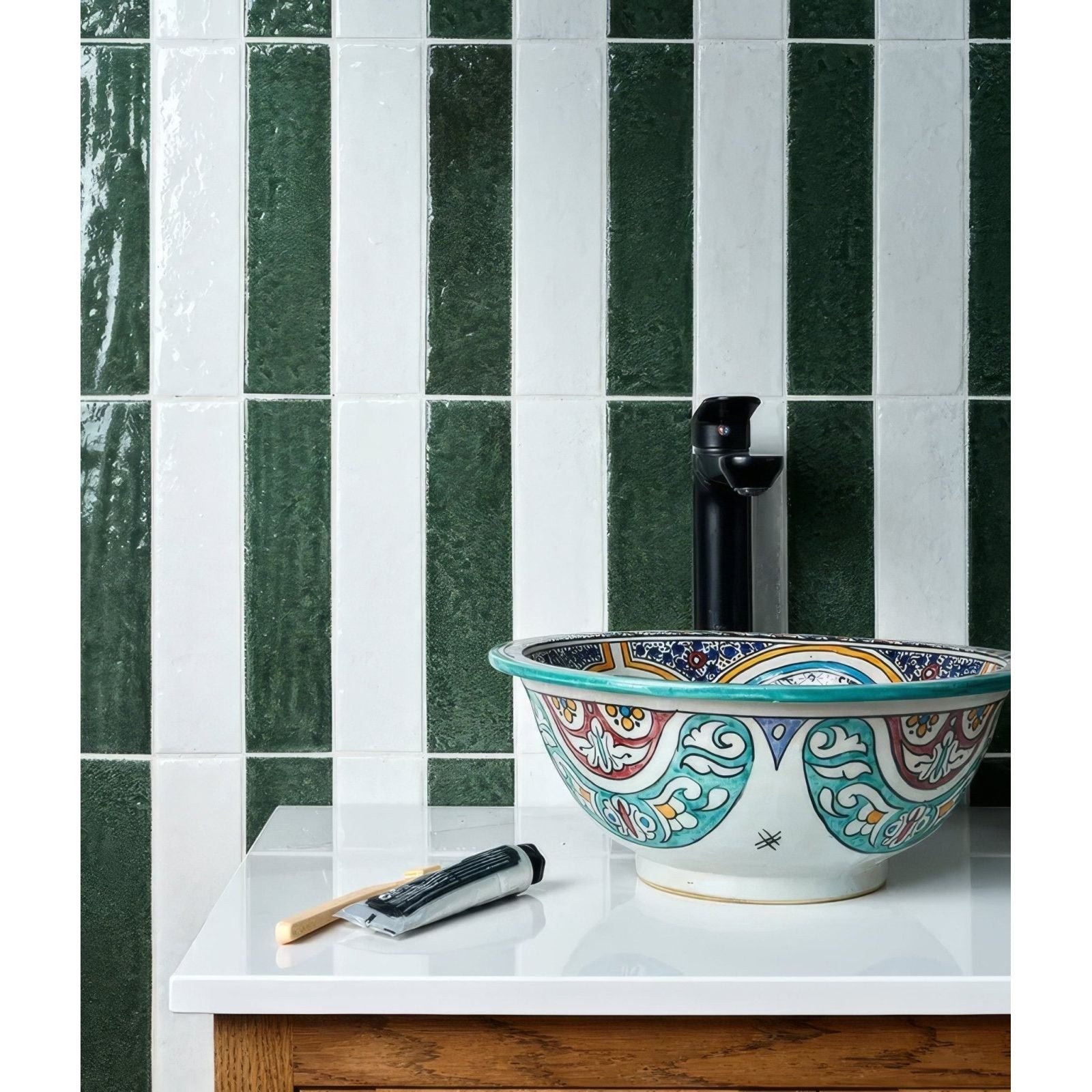 A colorful hand-painted ceramic vessel sink with floral and geometric patterns in teal red gold and blue