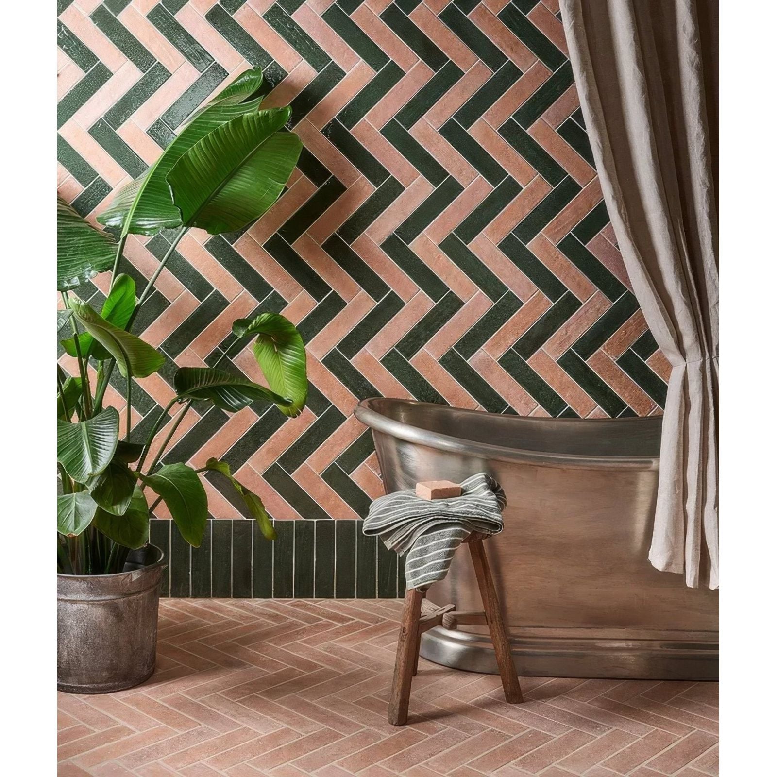 Antique brass bathtub with a striped towel draped over the side in marlborough porcelain parquet forest green gloss