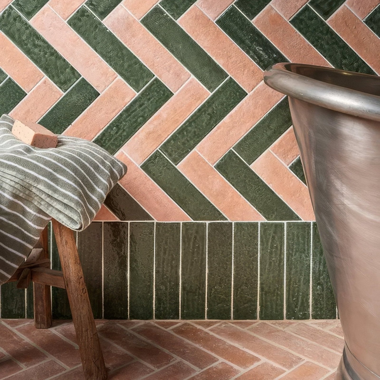 A rustic herringbone-patterned wall of marlborough porcelain parquet natural terracotta and deep green ceramic tiles