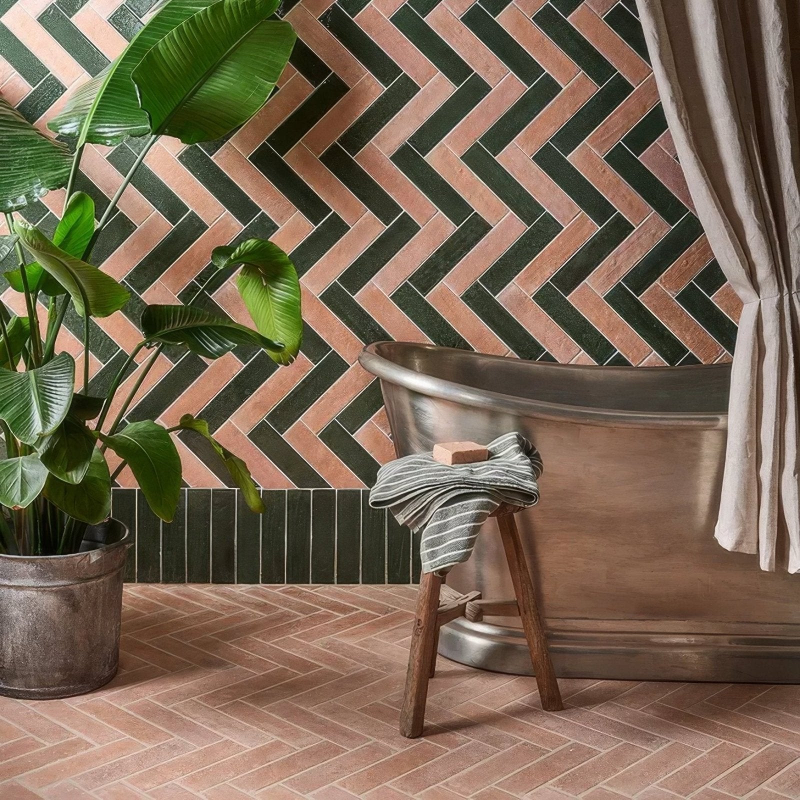 Antique brass clawfoot bathtub with rustic wooden stool draped in striped towel next to marlborough porcelain parquet natural
