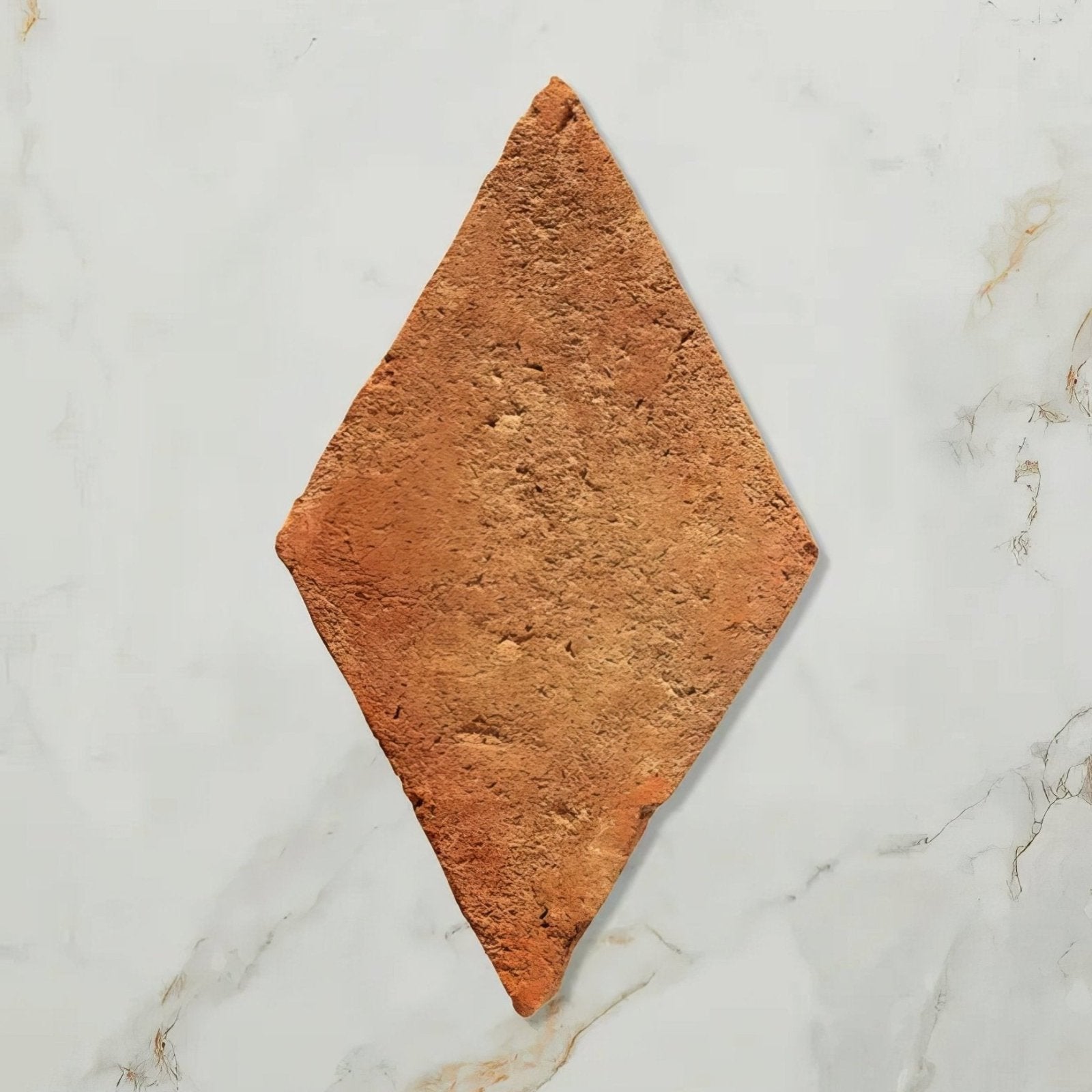A rustic terracotta marlborough terracotta diamond tile with a rough textured surface and diamond shape