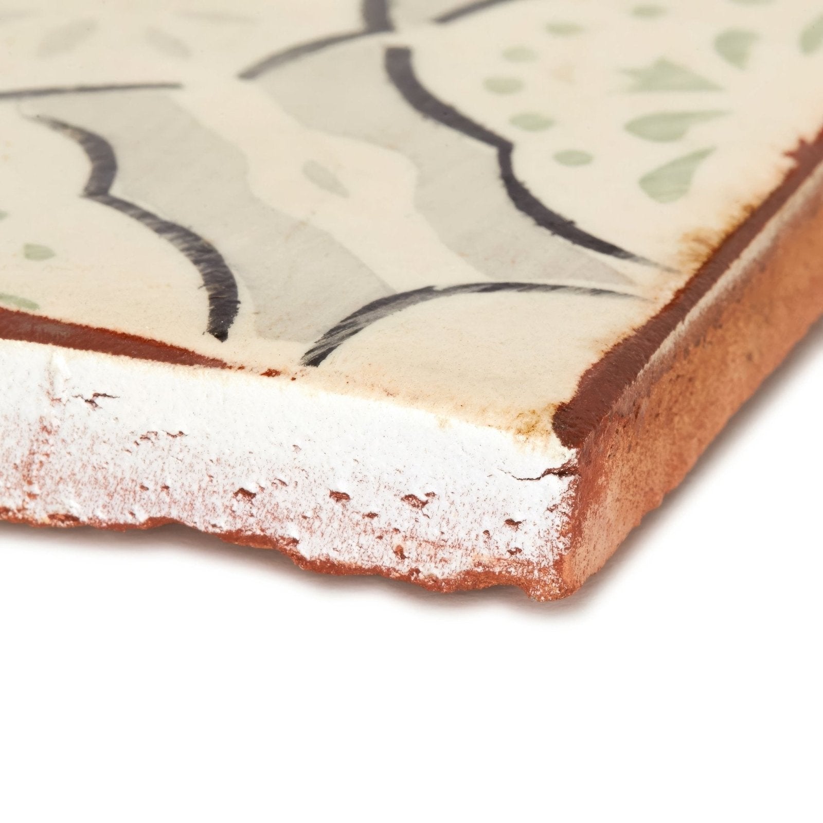 A rustic cream ceramic Marrakech Menara patterned terracotta tile with black and light green floral designs and exposed edge
