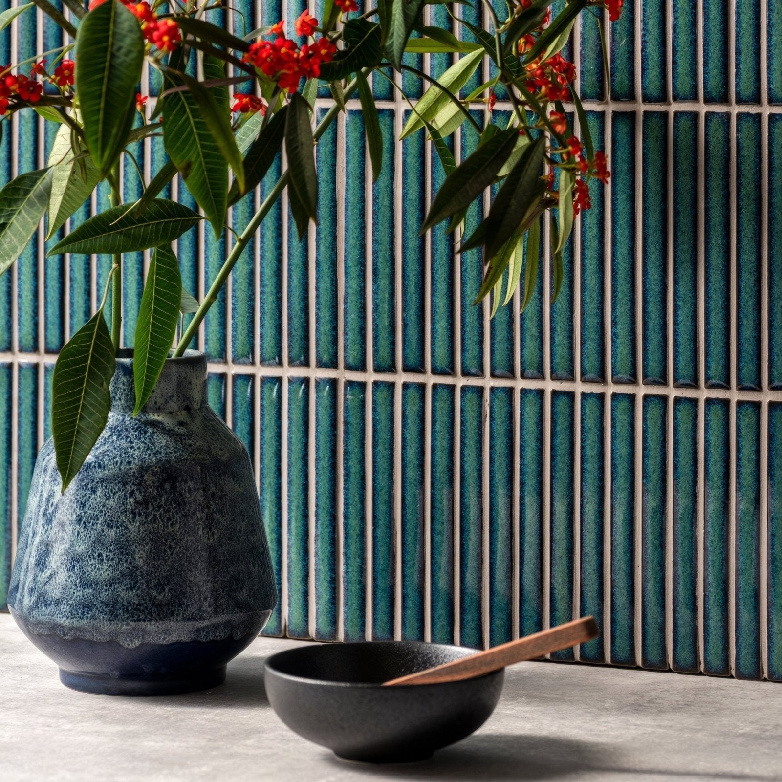 Matchstick Forest teal glass mosaic with a dark blue ceramic vase of flowers