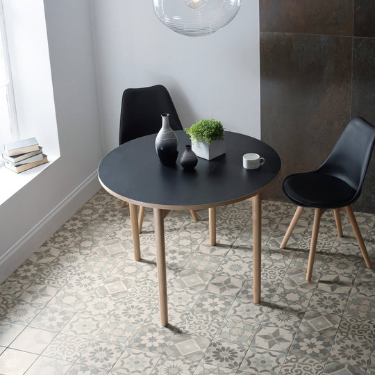 Black round dining table with light wood legs from Mezzo mixed melange collection for stylish dining spaces