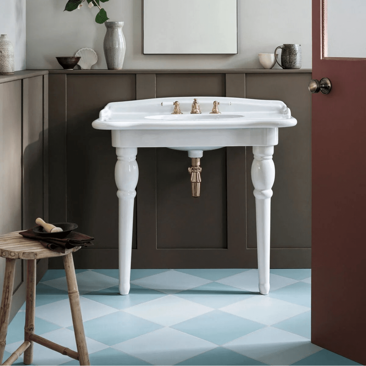 White ceramic pedestal sink with ornate gold-toned faucets and matching pipe complements milan gorani blue porcelain tile