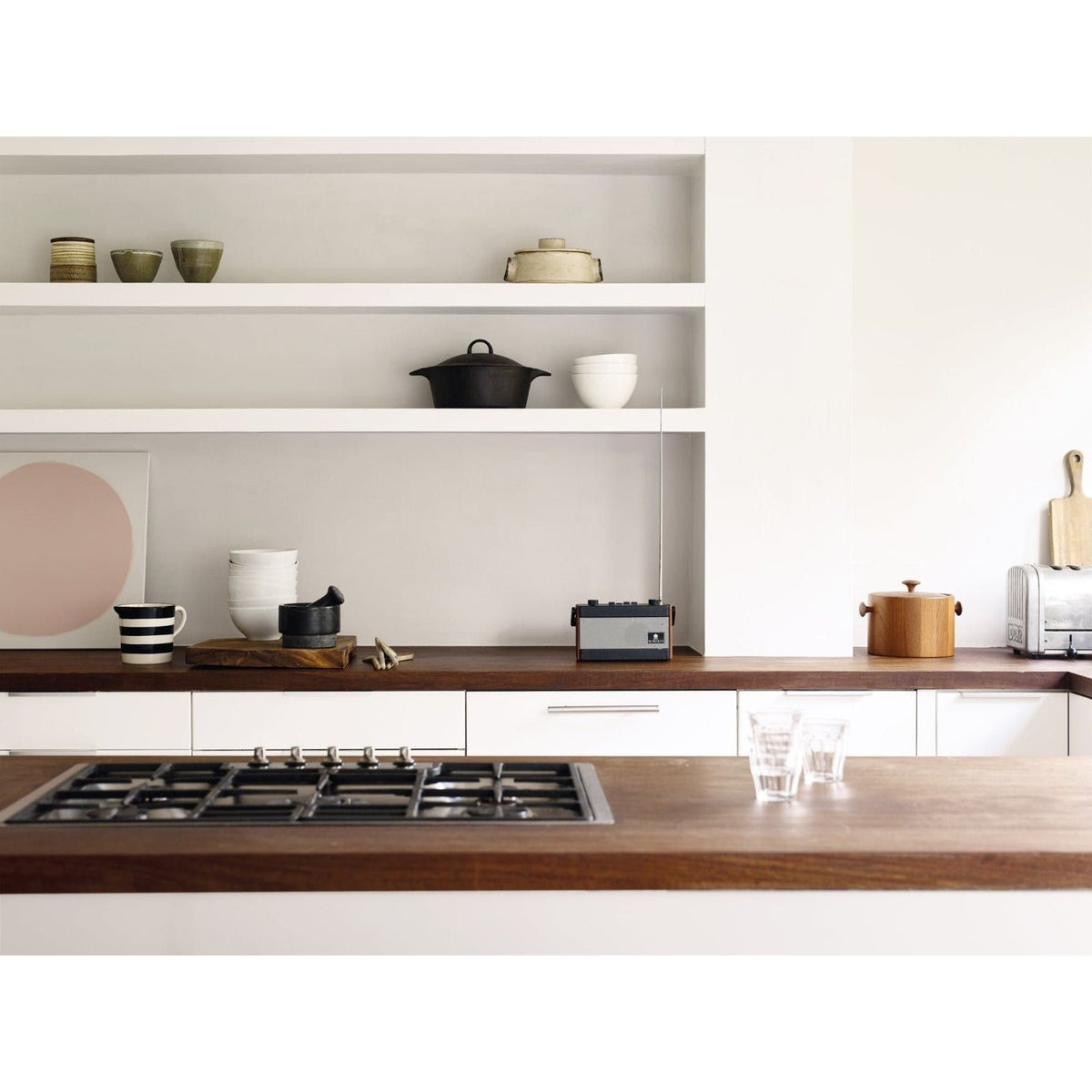 Black cast iron pot with handle and lid resting on wooden countertop from modernist white product line