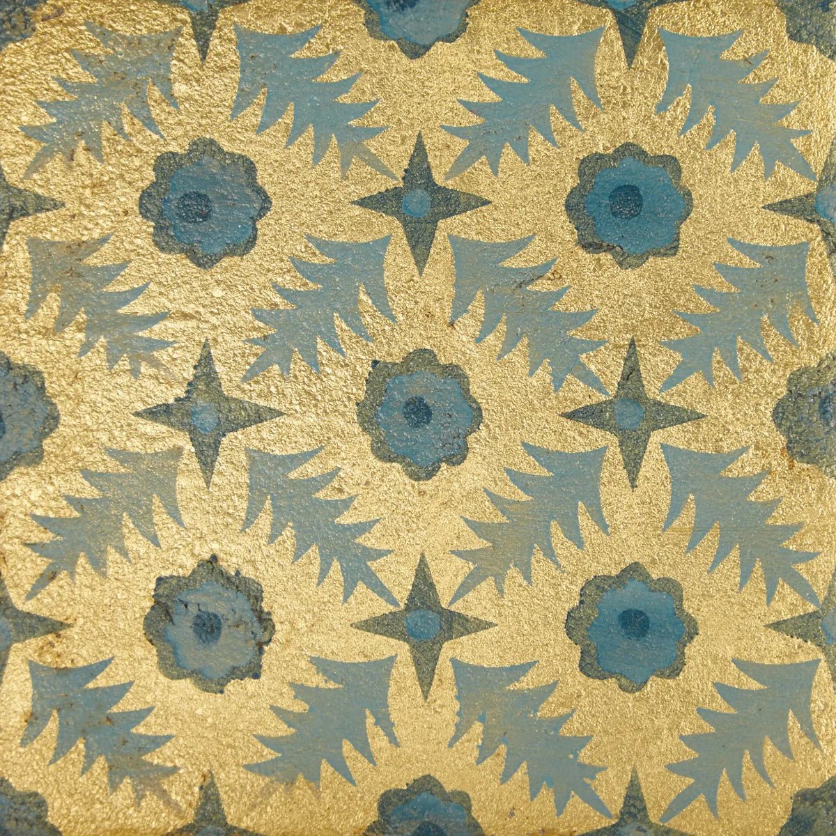 A decorative tile from neisha crosland atlas pine featuring a blue flower and star pattern on a gold textured background