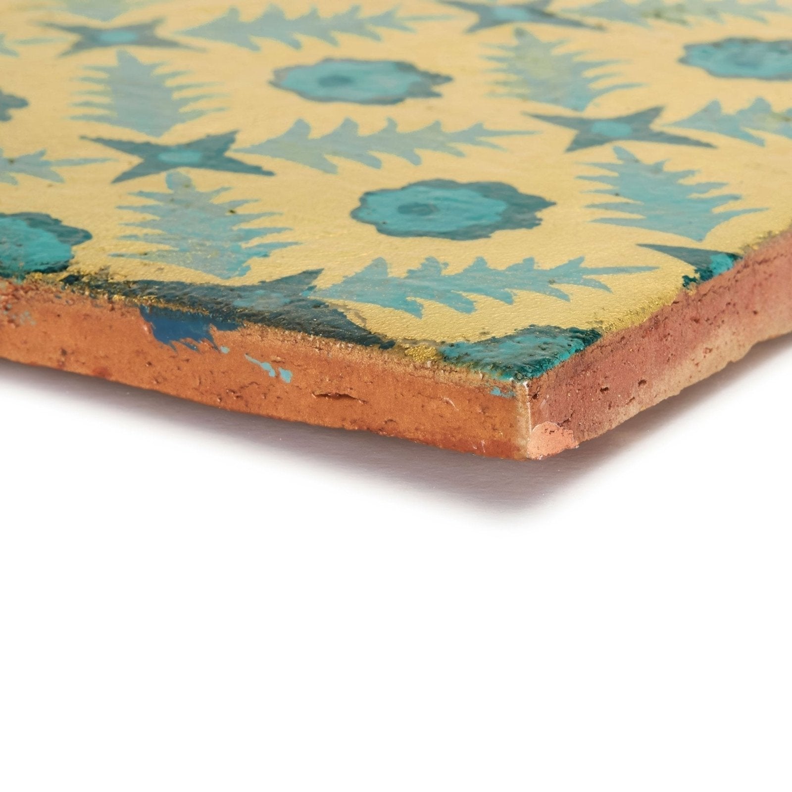 A hand-painted ceramic tile neisha crosland atlas pine flower nile with yellow background teal floral patterns and terracotta edges