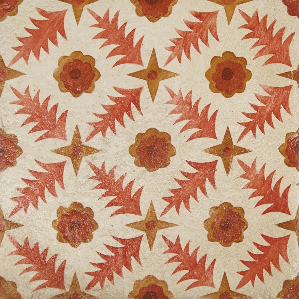 Patterned tile with repeating red and orange floral and star motifs on textured off-white background from neisha crosland atlas pine flower paprika