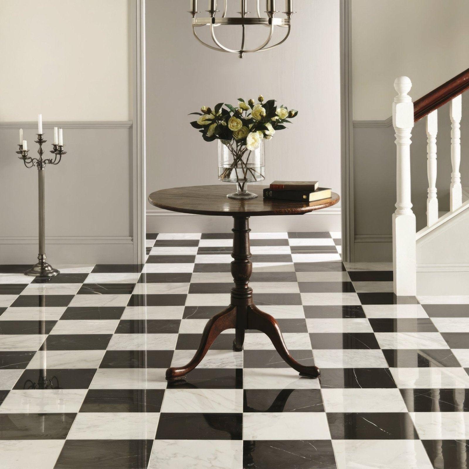 Dark wood nero polished marble round table with three curved legs and glass vase holding white roses on top