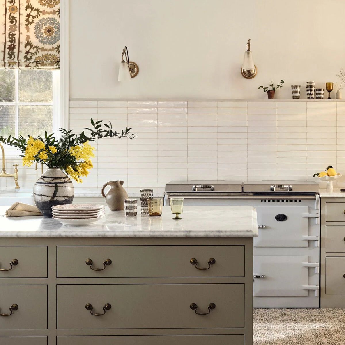 A ceramic vase with a black and white striped pattern holding yellow flowers paired with nina campbell rivage ivory glazed wall tile