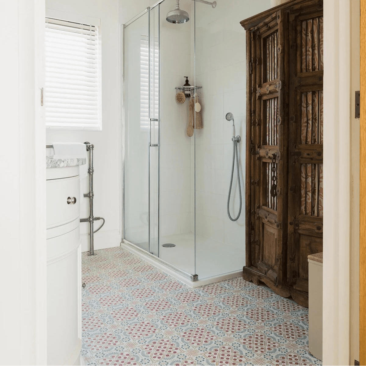 Glass shower enclosure with chrome fixtures and silver rainhead on nina campbell seville coral aqua porcelain tile wall